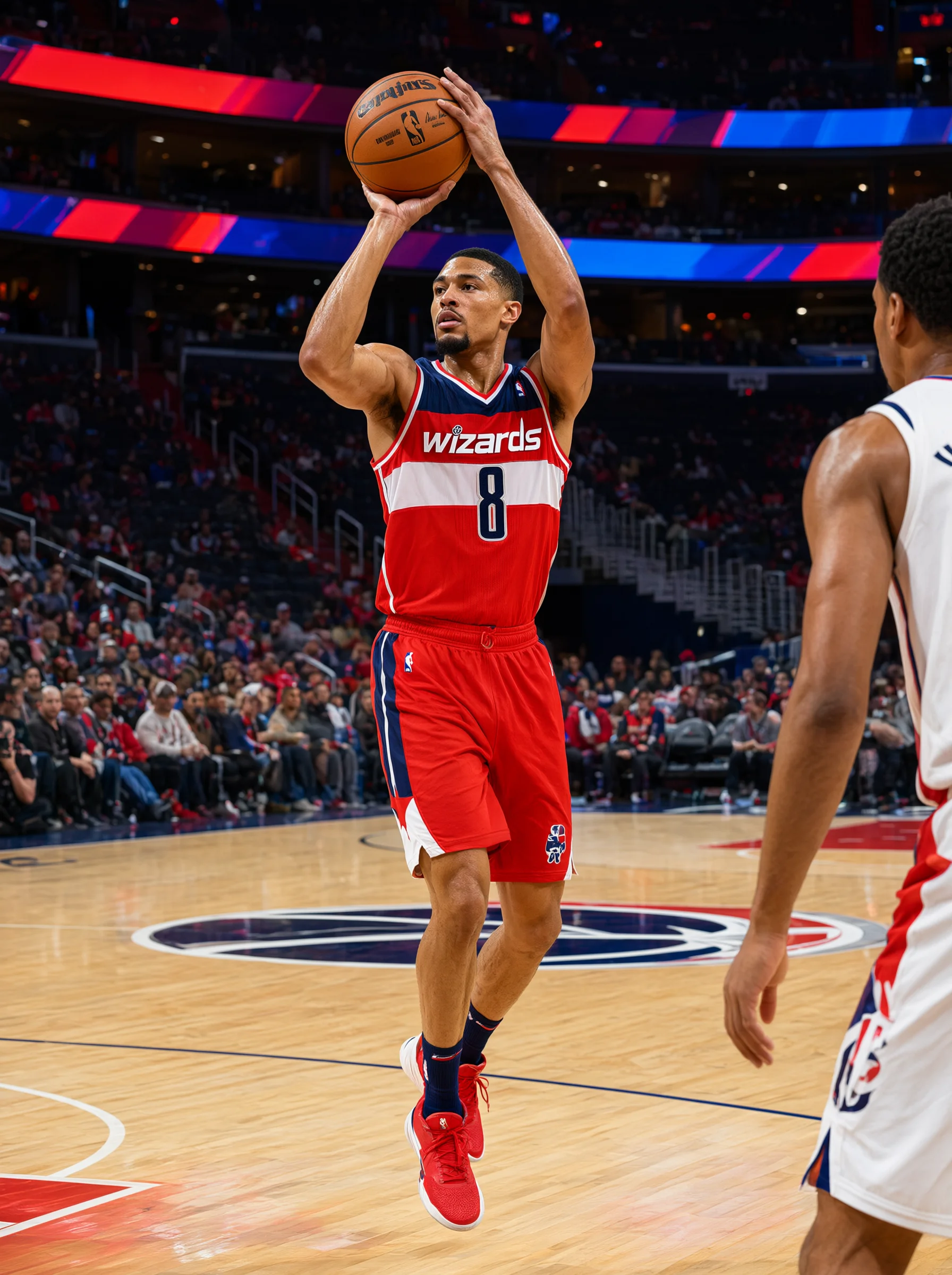 一名身穿红色Wizards 8号球衣的篮球选手在室内球场上跳起，双手将篮球举过头顶准备投篮；右侧前景有一名穿白色球衣的选手背影，背景是观众席和木质地板。